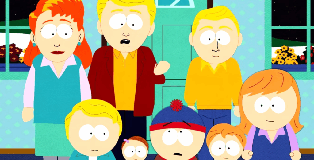 A large group of people are gathered together, including two boys of the main, along with several adults and children are all standing.