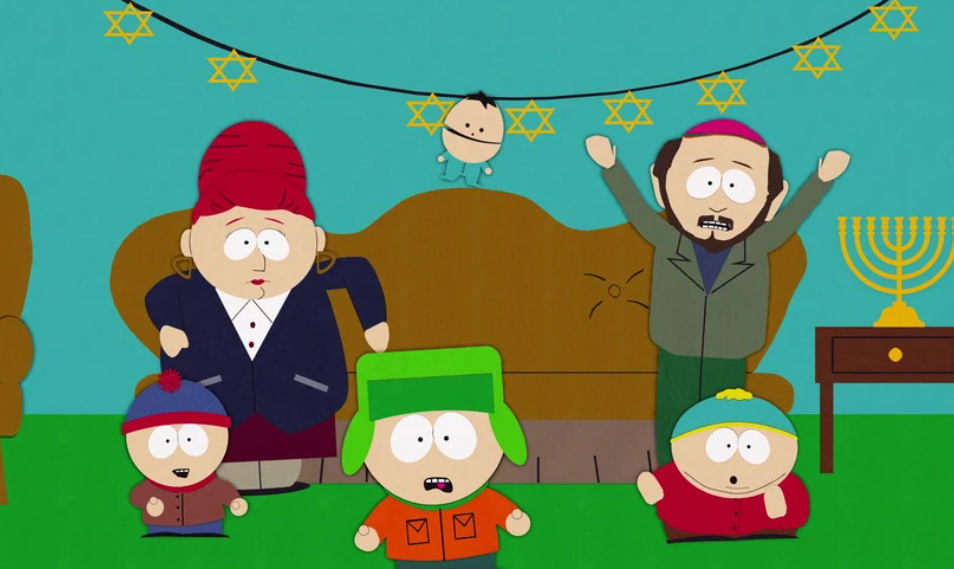 A group of five people, including Stan, Kyle, and Cartman are standing in front of two adults in a living room decorated for a Jewish holiday.