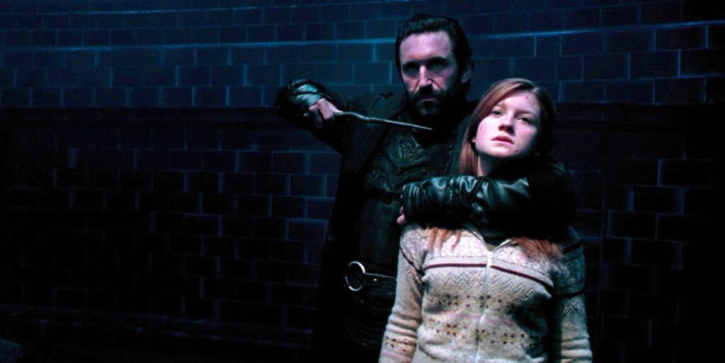 Death Eater Travers holding a wand at Ginny