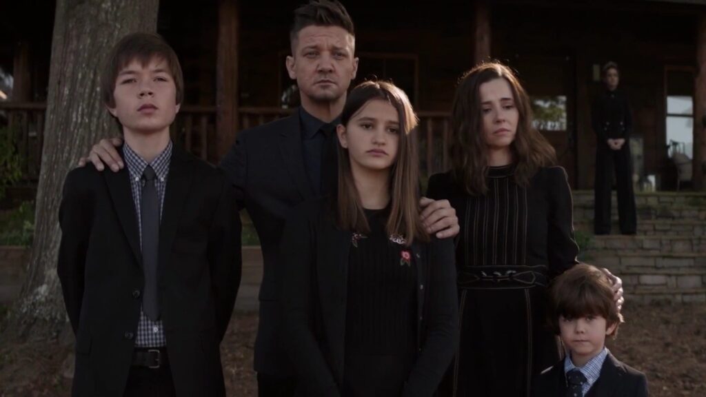 The Barton family - Clint Barton / Hawkeye in the center wearing dark clothing, surrounded by his wife Laura and their three children (Cooper, Lila, and Nathaniel), all dressed formally while attending Tony Stark's memorial service in MCU's Endgame.