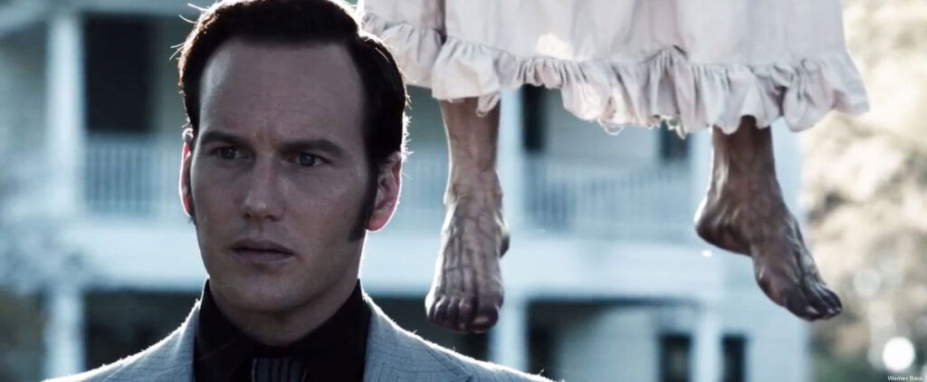 Ed Warren looking while two dangling feet are in the backdrop