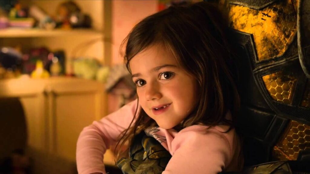 Young Cassie Lang as a child being held by Yellowjacket, smiling warmly while wearing a pink sweater in a cozy indoor setting.