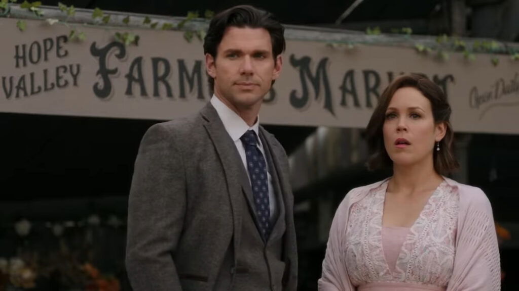Erin Krakow and Kevin McGarry standing at the Hope Valley Farmers Market while being stunned to hear a news.
