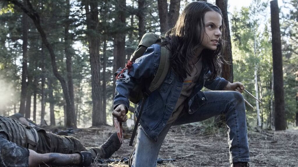 X-23/Laura Kinney crouched in a defensive position in a forest setting, with her adamantium claws extended and visible blood on them, wearing casual clothes and appearing ready for combat.