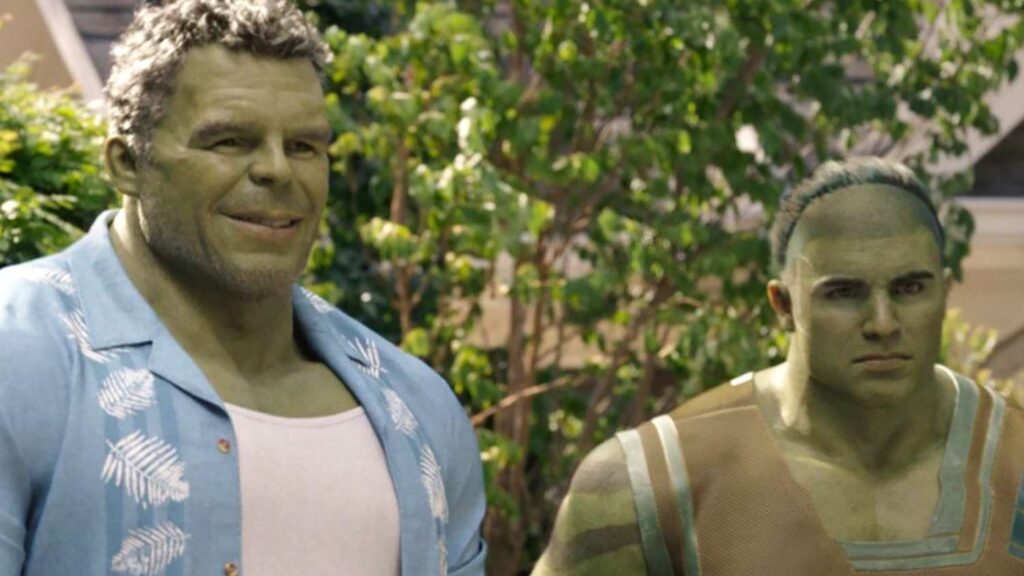 Bruce Banner / Hulk wearing a casual Hawaiian shirt, standing next to his son Skaar in his green Hulk form in an outdoor setting with trees in the background.