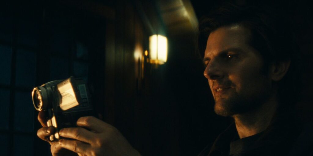 Adam Scott holding a camera in his hand and smiling in Severance, which won big at the Emmys 2025