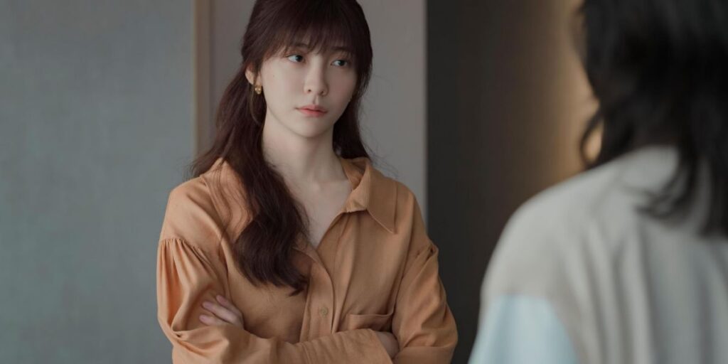 Scene from You and Everything Else with a character looking grim and her hands folded across her chest