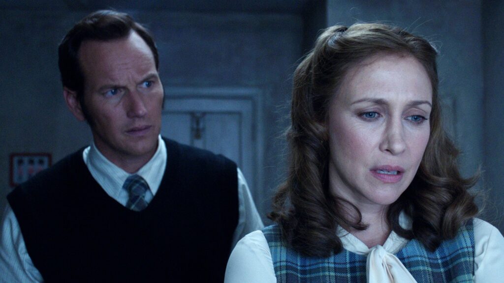 Patrick Wilson as Ed Warren and Vera Farmiga as Lorraine Warren in The Conjuring 2, dressed in 1970s clothing during their investigation of the Enfield Poltergeist case
