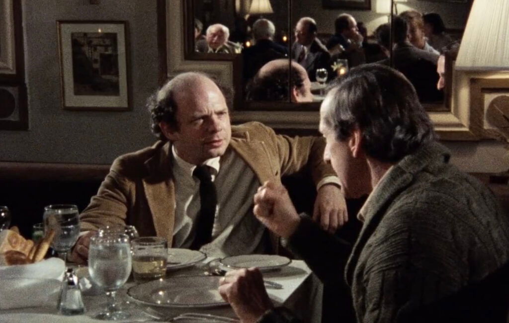 Two characters facing each other and eating in My Dinner With Andre