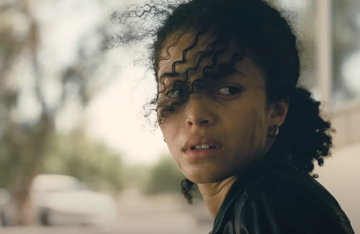A woman with dark curly hair in One Battle After Another