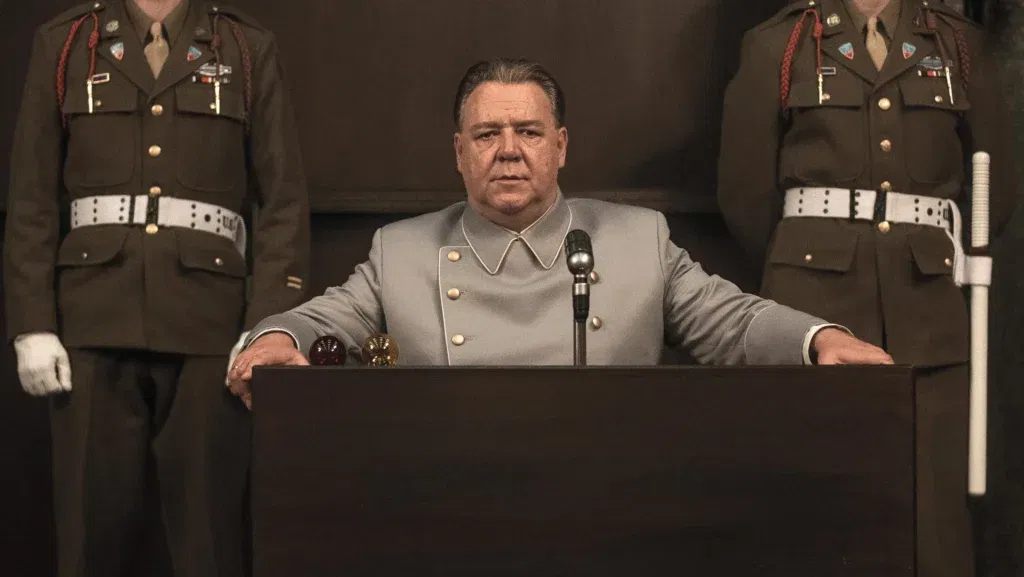 Russell Crowe sitting while two officials stand beside him
