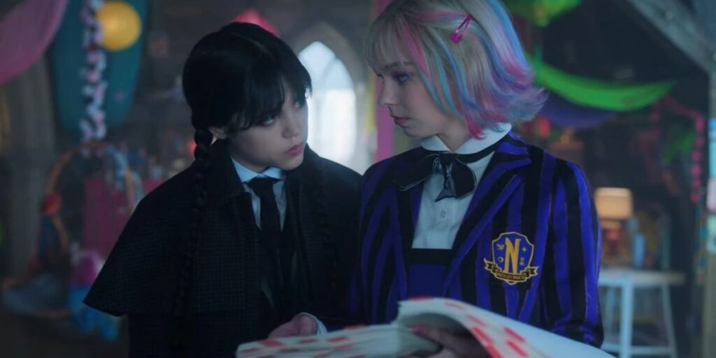 Enid Sinclair holding a book and Wednesday Addams looking at Enid in Wednesday season 2