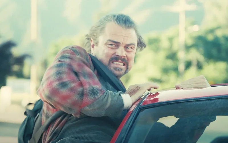 Leonardo DiCaprio, jumping out of a car in One Battle After Another.