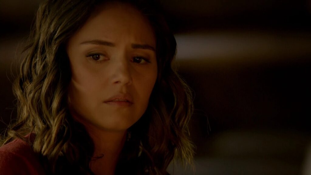 Leslie-Anne Huff as Rayna Cruz with wavy hair looking emotional with tears in her eyes, photographed in warm indoor lighting.