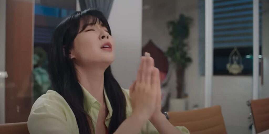 A woman folds her hands and closes her eyes to pray