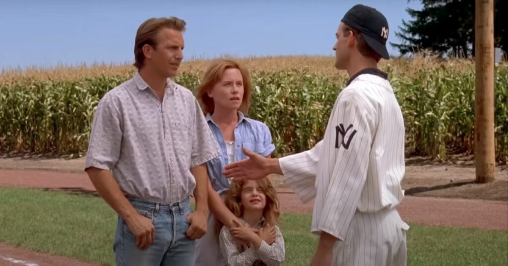 a still from the 1989 film Field of Dreams, featuring Kevin Costner as Ray Kinsella, Amy Madigan as Annie Kinsella, Gaby Hoffmann as Karin Kinsella, and Dwier Brown as John Kinsella
