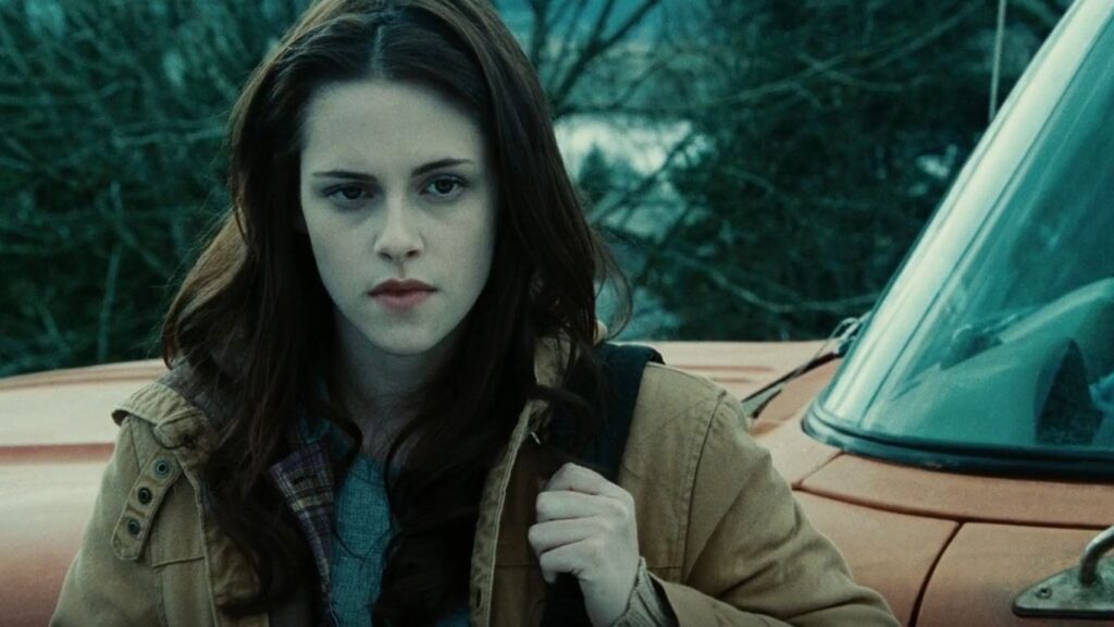 Bella Swan (Kristen Stewart) stands next to her car looking contemplative, with her characteristic serious expression.