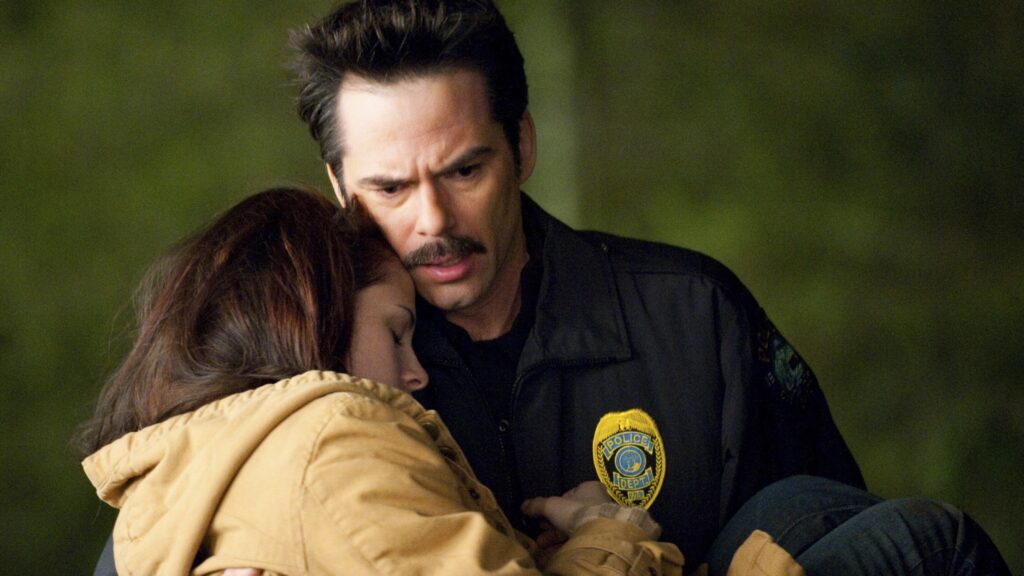 Charlie Swan (Billy Burke) in his police uniform carriess Bella (Kristen Stewart) who is wearing a yellow jacket in a still from The Twilight Saga: New Moon.