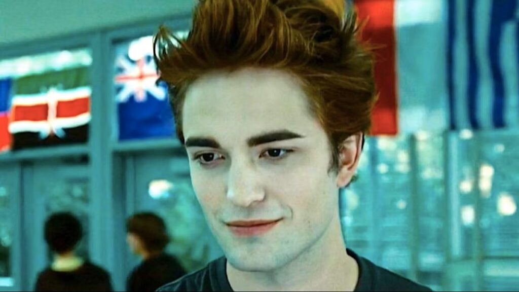 Edward Cullen (Robert Pattinson) in the high school cafeteria with his distinctive bronze hair and pale complexion, capturing his mysterious and otherworldly appearance as introduced in the first film.