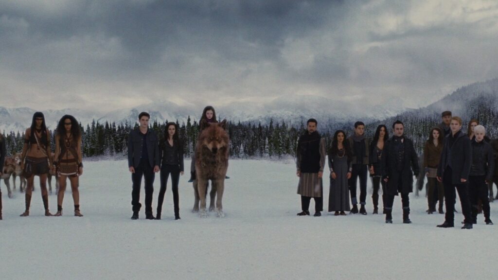 The Cullens with other vampires and Jacob (in wolf form) stand in a snowy field with mountains and forest in the background, preparing for the final confrontation in Breaking Dawn Part 2.