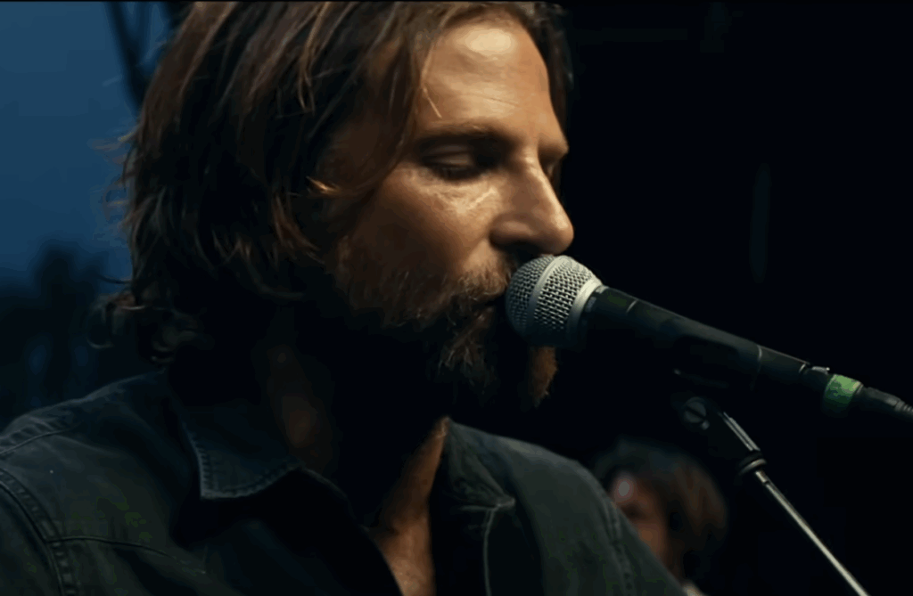 Bradley Cooper, singing into a microphone. 