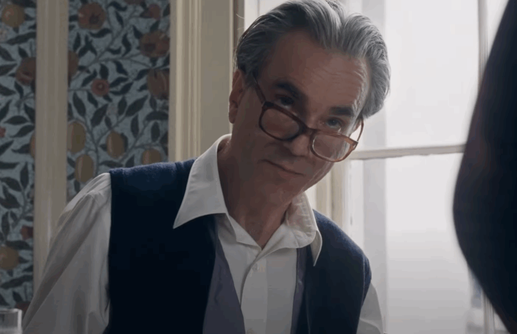 Daniel Day-Lewis in a black tux and glasses, sitting at a dining table. 