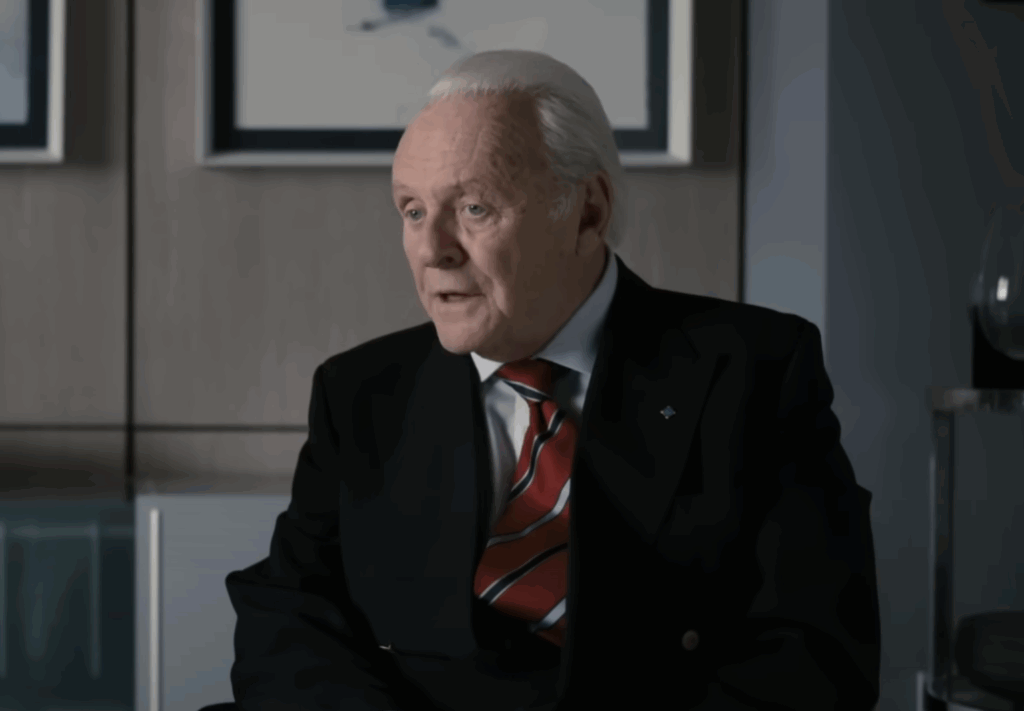 Anthony Hopkins in a red tie and a black suit. 