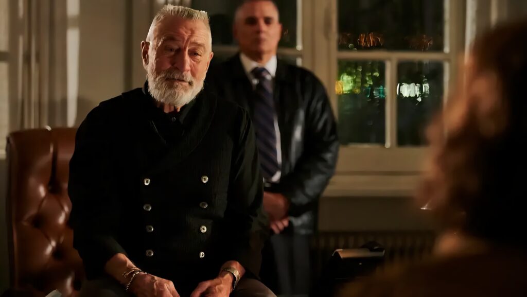 An old man in his dress blues leans against a desk