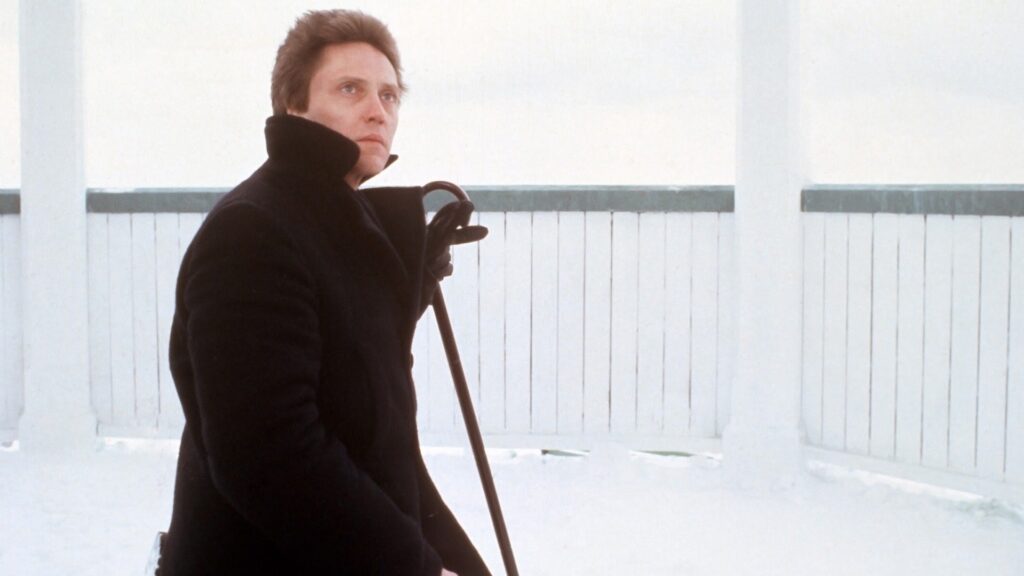 Christopher Walken sitting with a cane
