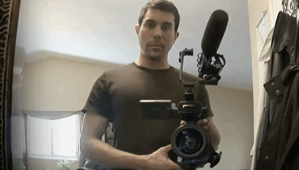 A man holding up a camera attached with a microphone in Paranormal Activity.