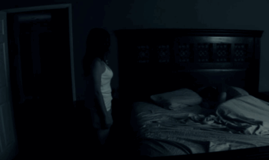A woman standing up straight in the middle of the night in Paranormal Activity.
