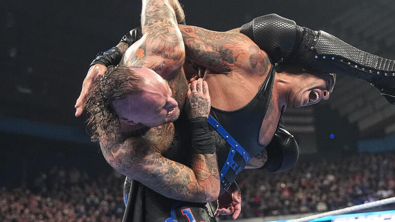 Aleister Black locking Damian Priest in a submission hold