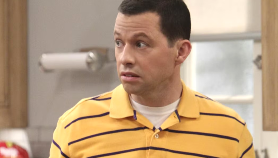 Alan Harper is wearing a yellow polo shirt and looking to the side with a shocked expression.