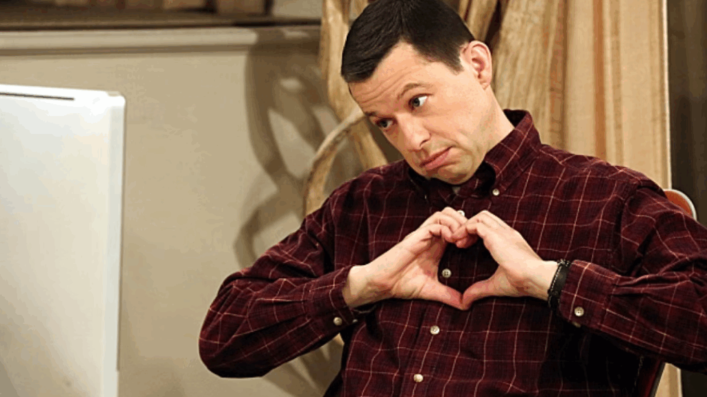 Alan Harper is looking at someone and making a heart shape with his hands.
