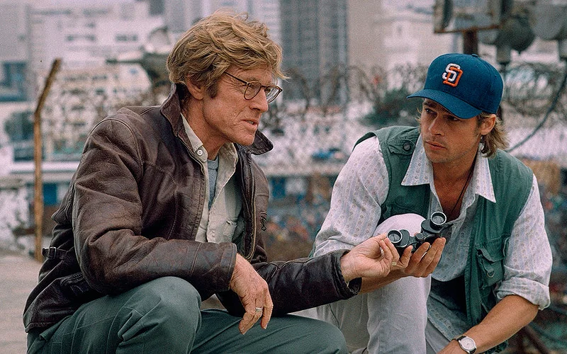 Robert Redford handing something to Brad Pittin Spy Games.