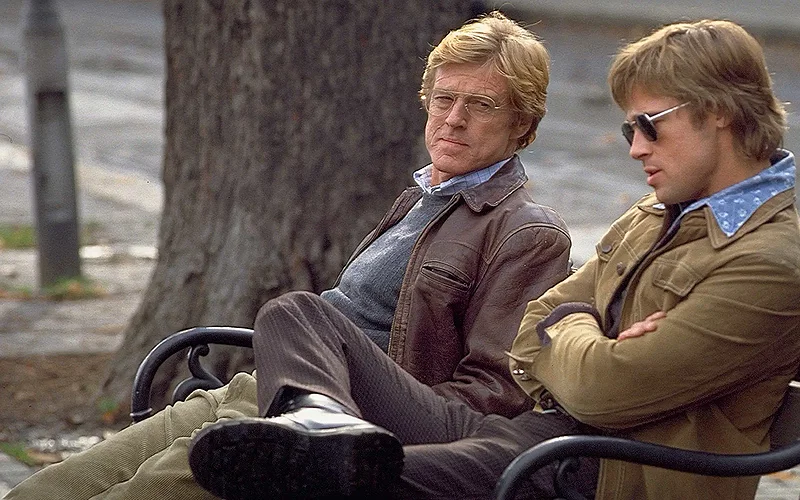 Brad Pitt and Robert Redford sitting on a park bench