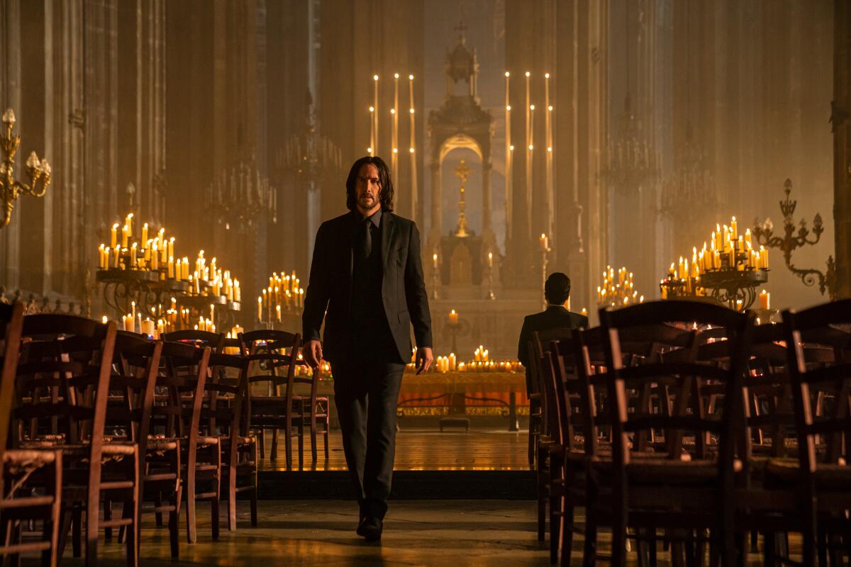 Keanu Reeves in his dark black suit as John Wick walking out of a church 
