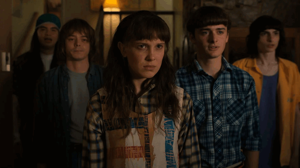 The cast of Stranger Things looking with curiosity in a still from the show.