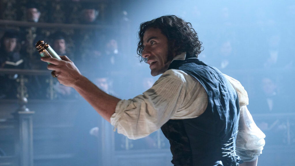 Oscar Isaac as Victor Frankenstein holding an object in hand in Guillermo del Toro’s movie.