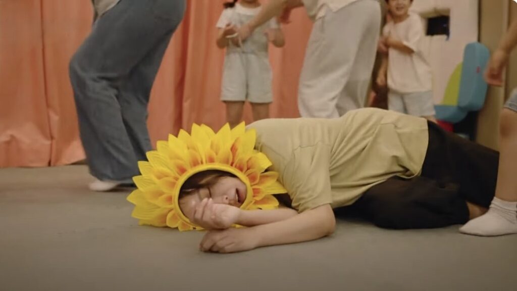 No Next Life Season 1 Episode 2: Release Date, Time & Where to Watch 52 Comedic scene from No Next Life showing Kim Hee-sun wearing sunflower headpiece lying on floor during party