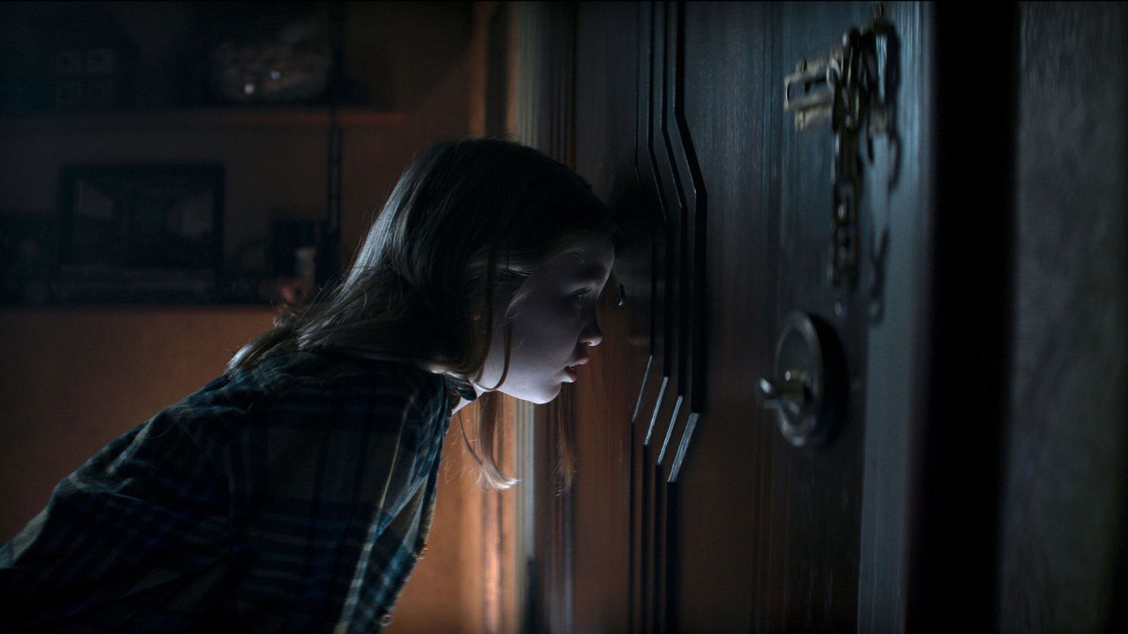 Nell Fisher as Kassie looking through peephole at door in tense Evil Dead Rise scene