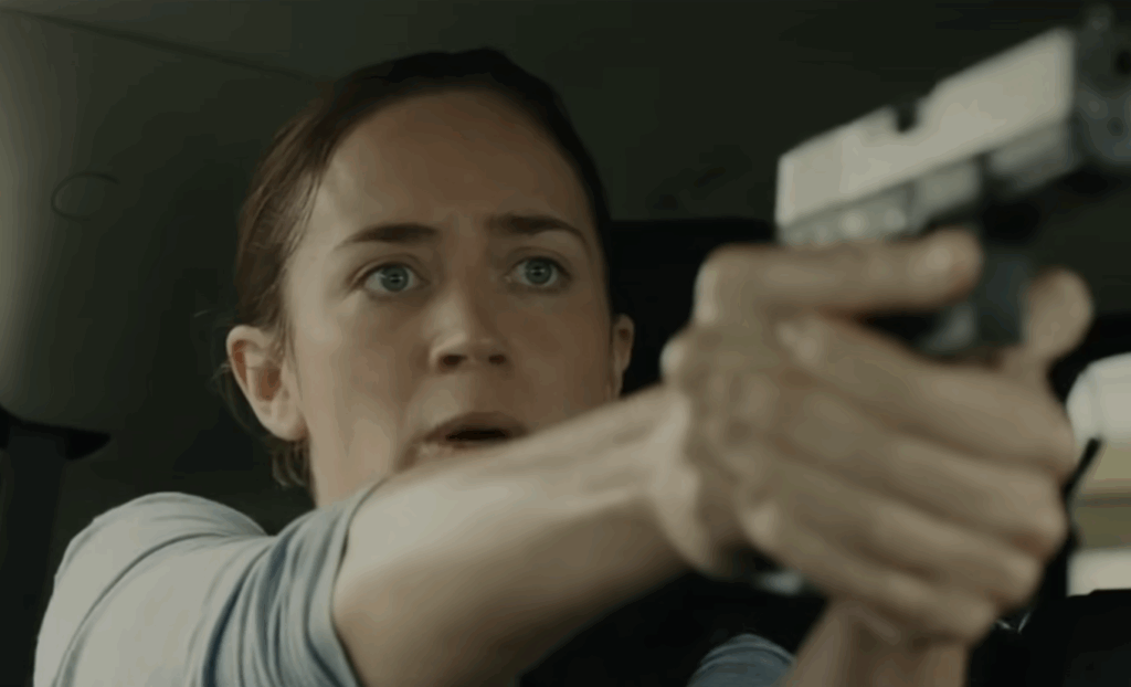 Emily Blunt as Kate Macer pointing a gun looking startled in Sicario 2