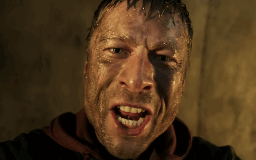 Glenn Powell covered in mud and water 