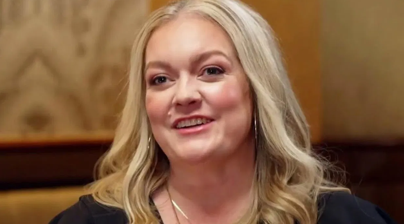 Colleen Hoover is wearing large hoop earrings and smiling brightly.