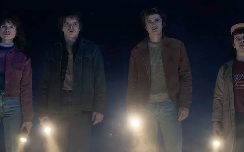 Nancy, Jonathan, Steve, and Dustin are standing side-by-side in the dark.