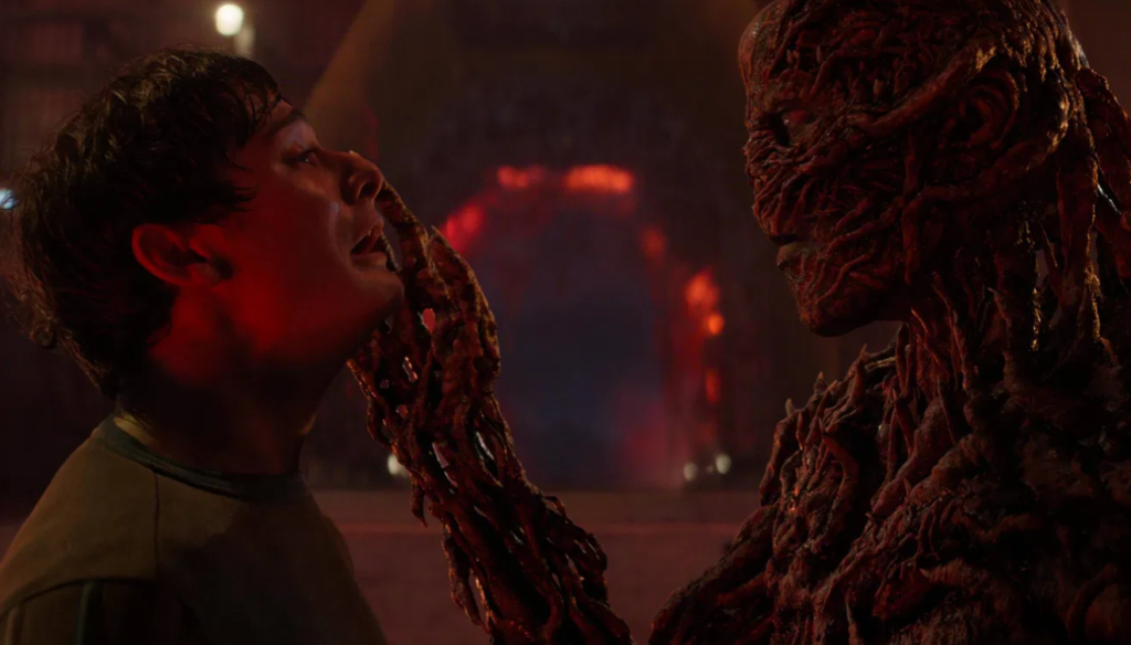 Vecna is grabbing Will's face with his vine-like hand.