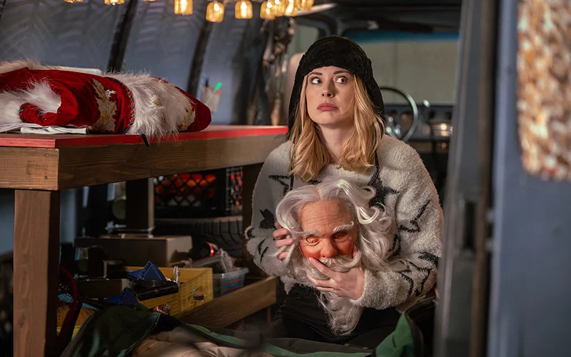 A still from My Secret Santa featuring Taylor holding a Santa mask while sitting in the back of a van