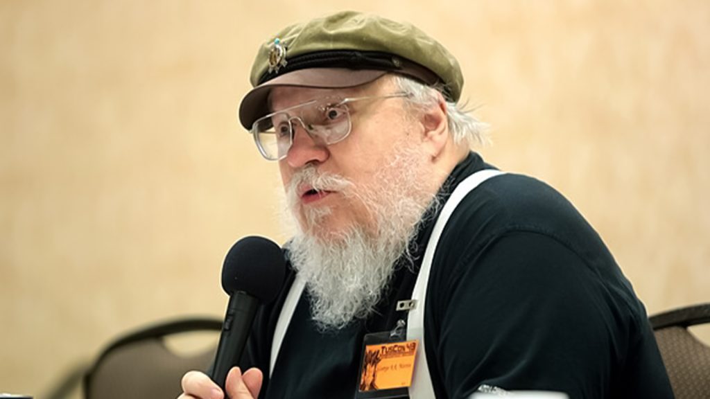 George R. R. Martin speaking into a mic at a Game of Thrones event. 