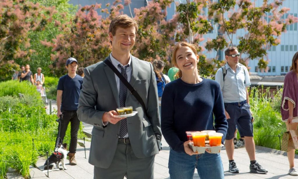 A still from Set It Up starring Glen Powell and Zoey Deutch, both carrying food