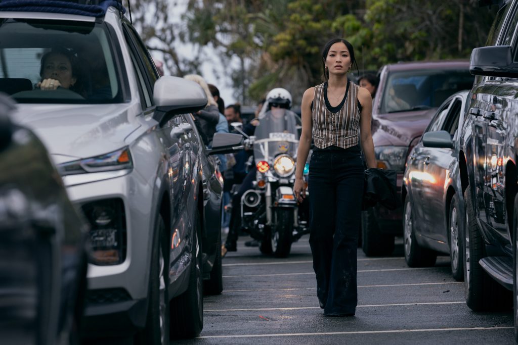 A still from Monarch: Legacy of Monsters Season 2 featuring Cate walking down a busy street surrounded by cars